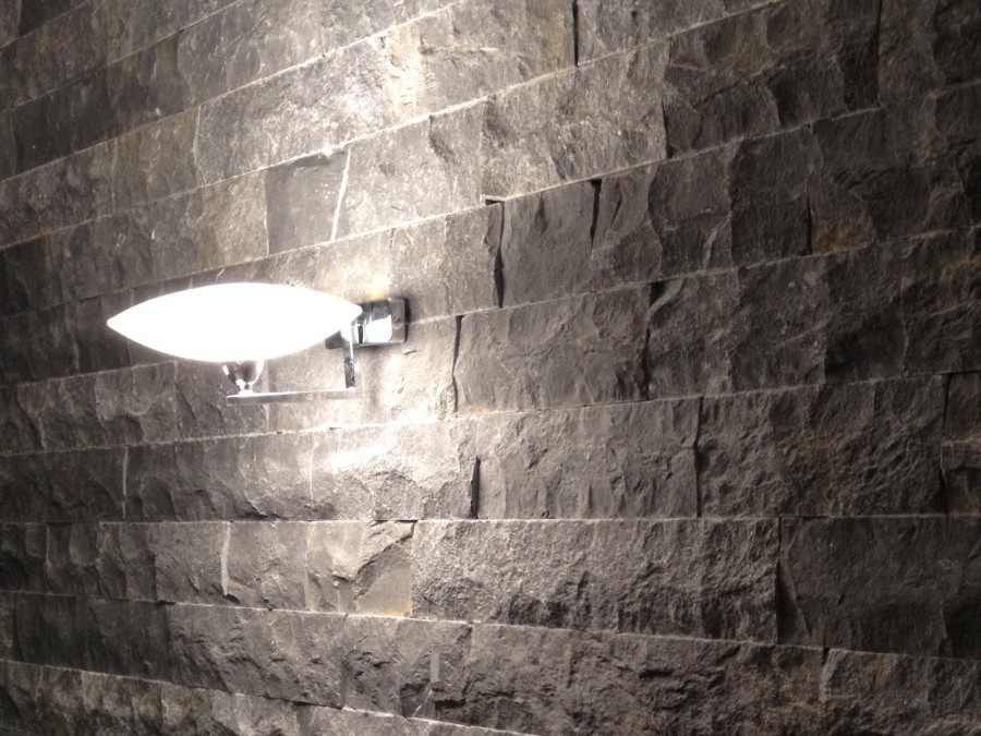 Doğal taş döşenmiş duvar üzerinde beyaz aplik aydınlatma